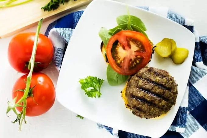 Horizontal image of healthy burgers with tomatoes sitting beside them.