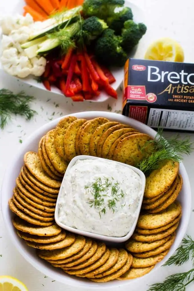 Horseradish Dill Schmear on a white plate with a box of Breton crackers.