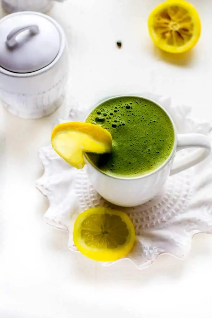 Matcha Green Tea Latte on a white saucer with lemon