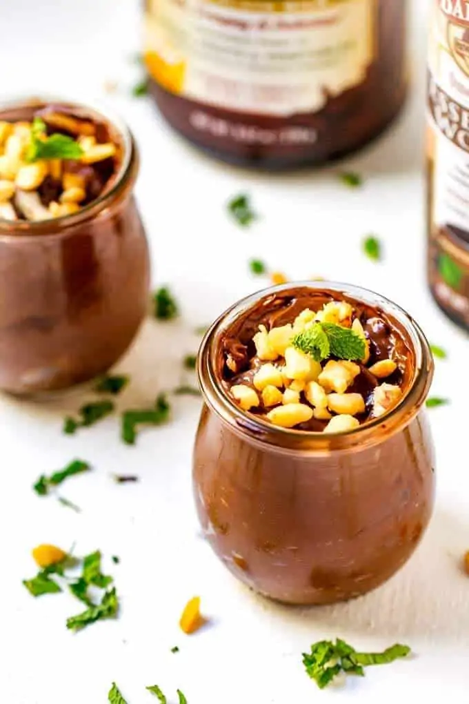 Two small jars of Chocolate Mint Avocado Pudding with mint scattered
