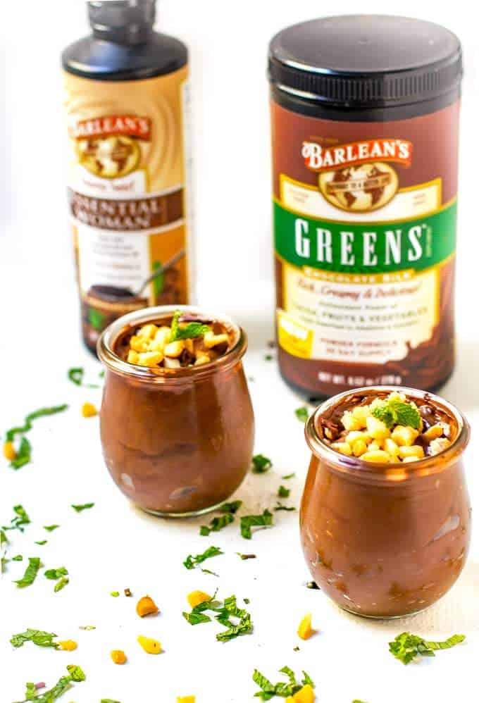 Two jars of Chocolate Mint Avocado Pudding with Barleans Greens and Omegas in the background