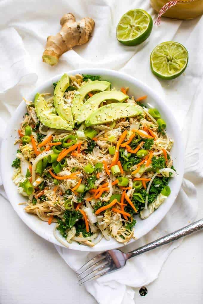 Overhead photo of Asian Chicken Salad in a white plate on a white backgroundwith lime and ginger