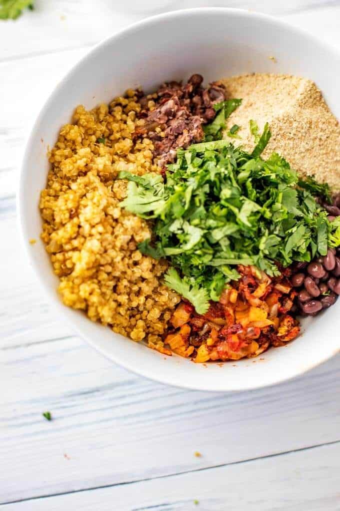 Photo of quinoa, black beans, breadcrumbs, cilantro, chipotle chili pepper, onion, garlic, and spices in a white bowl.