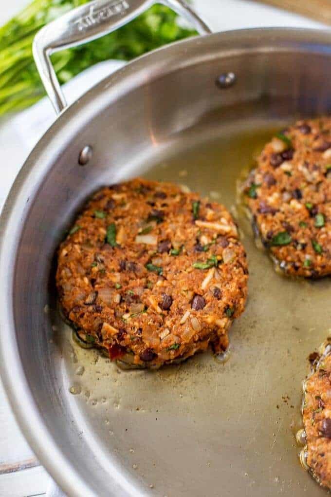 Photo of Black Bean Quinoa Burger Patties cooking in a skillet.