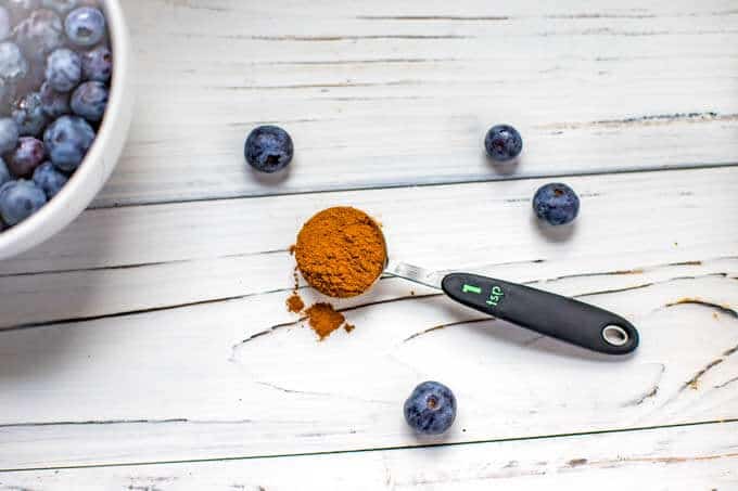 Photo of a teaspoon of cinnamon and blueberries for a Blueberry Banana Smoothie