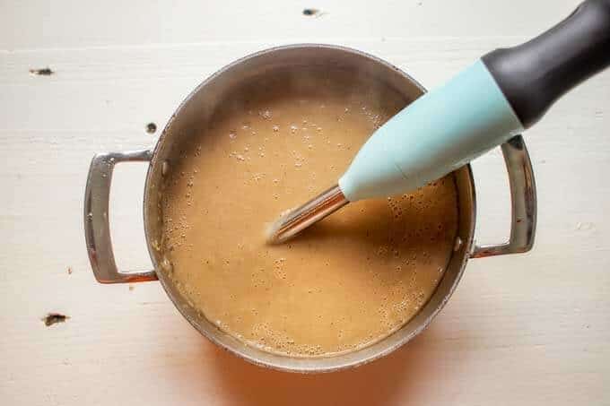 Photo of cauliflower potato soup being blended with an immersion blender.