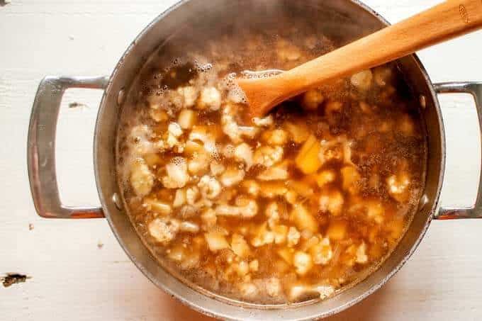 Photo of cauliflower and potatoes being cooked in broth.