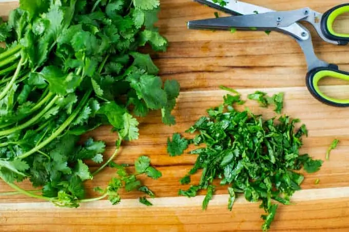 Cutting board with cilantro being prepped for turmeric rice.