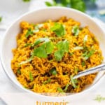 Photo of Turmeric Rice in a white bowl garnished with cilantro with the text Turmeric Rice below.