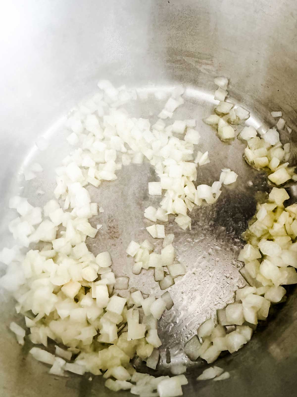 Onion cooking in oil in a saucepan.