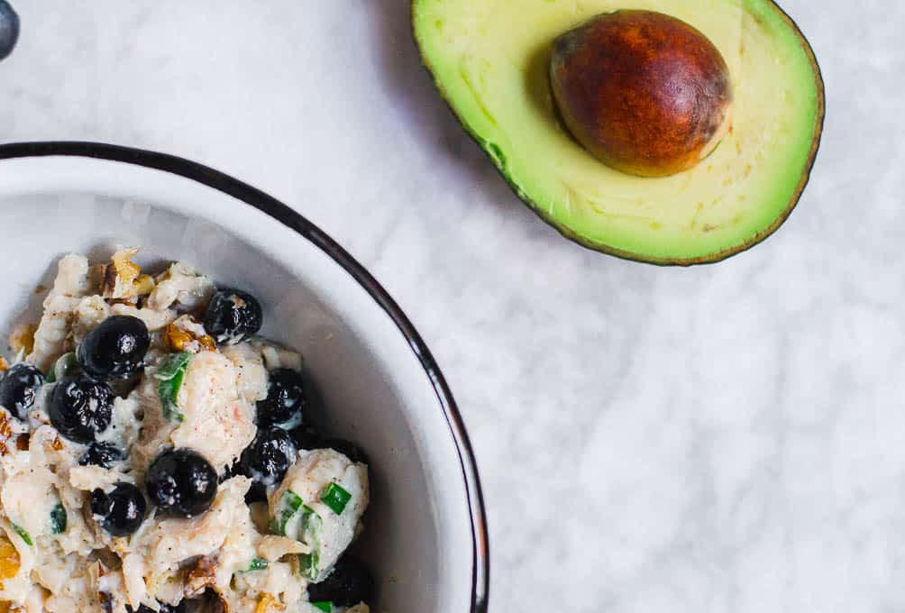 Bowl of blueberry chicken salad and an avocado