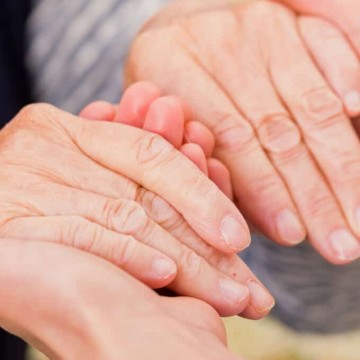 Photo of younger hands holding older hands.