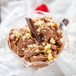 Square photo of homemade chocolate ice cream garnished with macadamia nuts in a glass dish.
