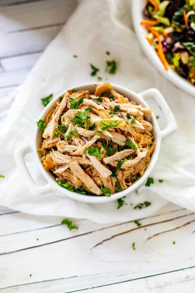 Overhead photo of Instant Pot Shredded Chicken Breast in a white dish garnished with parsley