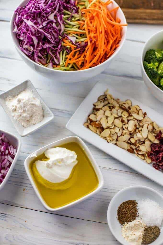 Photo of the ingredients - Greek yogurt, olive oil, lemon juice, Swerve, garlic powder, celery seed, cayenne pepper, salt, and pepper, broccoli, broccoli slaw, red onion, almonds, carrots, cabbage, cranberries.