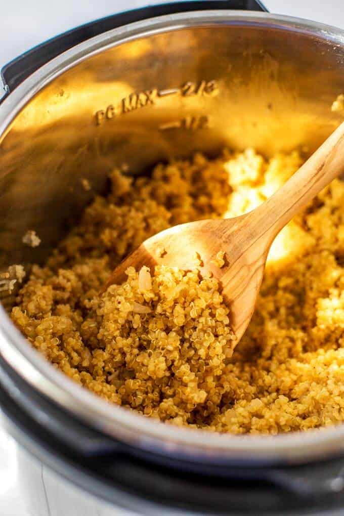 Photo of cooked quinoa in an instant pot with a wooden spoon in it.