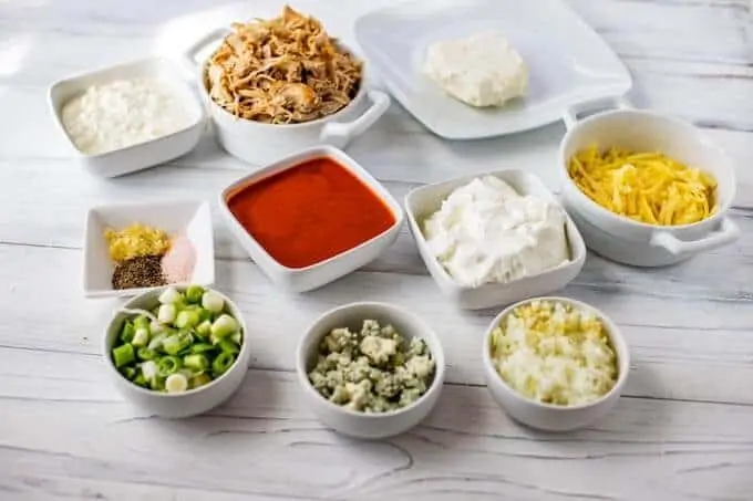 Photo of the ingredients for a Healthy Buffalo Chicken Dip with Greek Yogurt, cottage cheese, low fat cream cheese, chicken, cheese, seasonings, scallions, blue cheese onion and garlic.