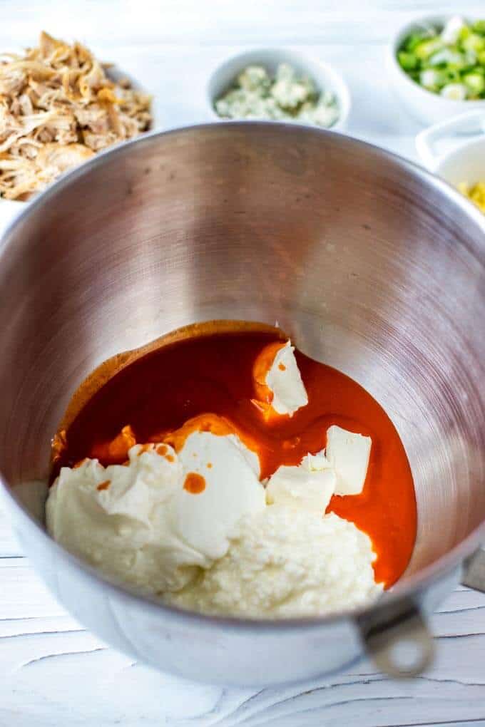 Photo of wet ingredients for a Low Calorie Buffalo Chicken Dip being mixed together in a large mixing bowl.