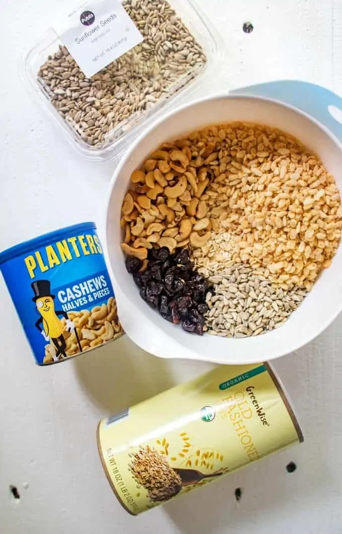 Photo of dry ingredients for a homemade granola bar recipe mixed together in a bowl with the ingredient packaging surrounding.