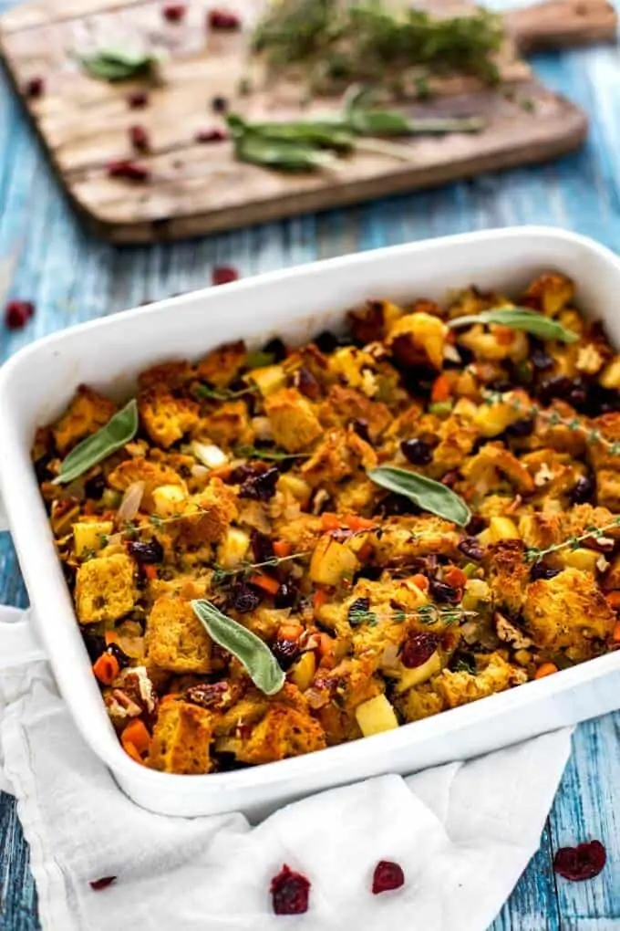 Photo of Gluten Free Stuffing in a white casserole dish garnished with sage and thyme.