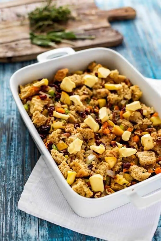 Photo of gluten free stuffing in a white casserole dish with butter dotted over it.