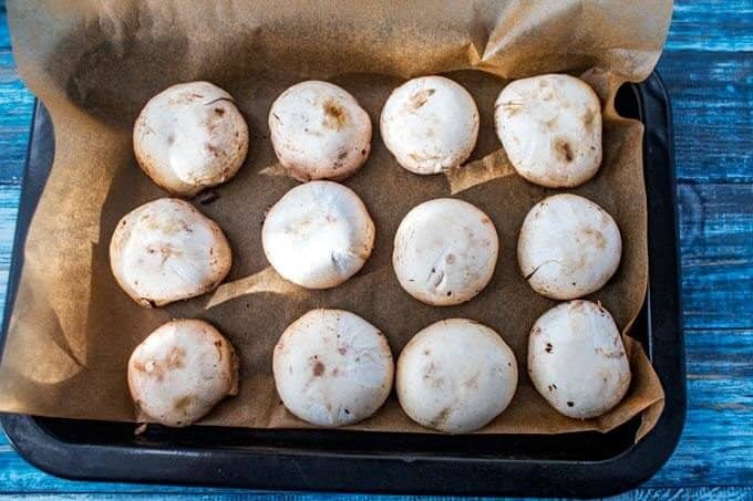 Sheet pan with mushrooms on it stem side down.