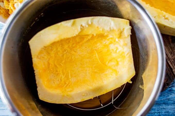 Second process photo for Instant Pot Spaghetti Squash. Uncooked spaghetti squash is being added to the Instant Pot.