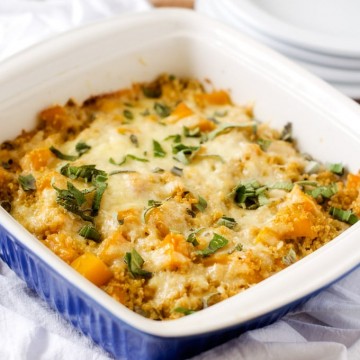Photo of Butternut Squash Casserole with Quinoa in a blue casserole dish with serving plates behind it.