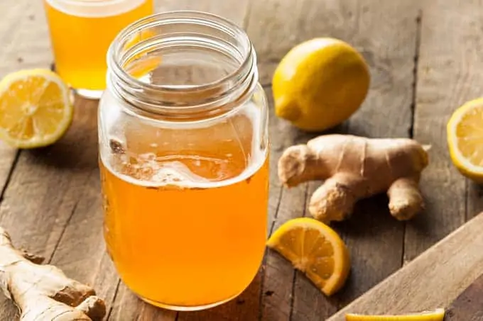 Photo of kombucha in a mason jar with lemon and ginger around it.