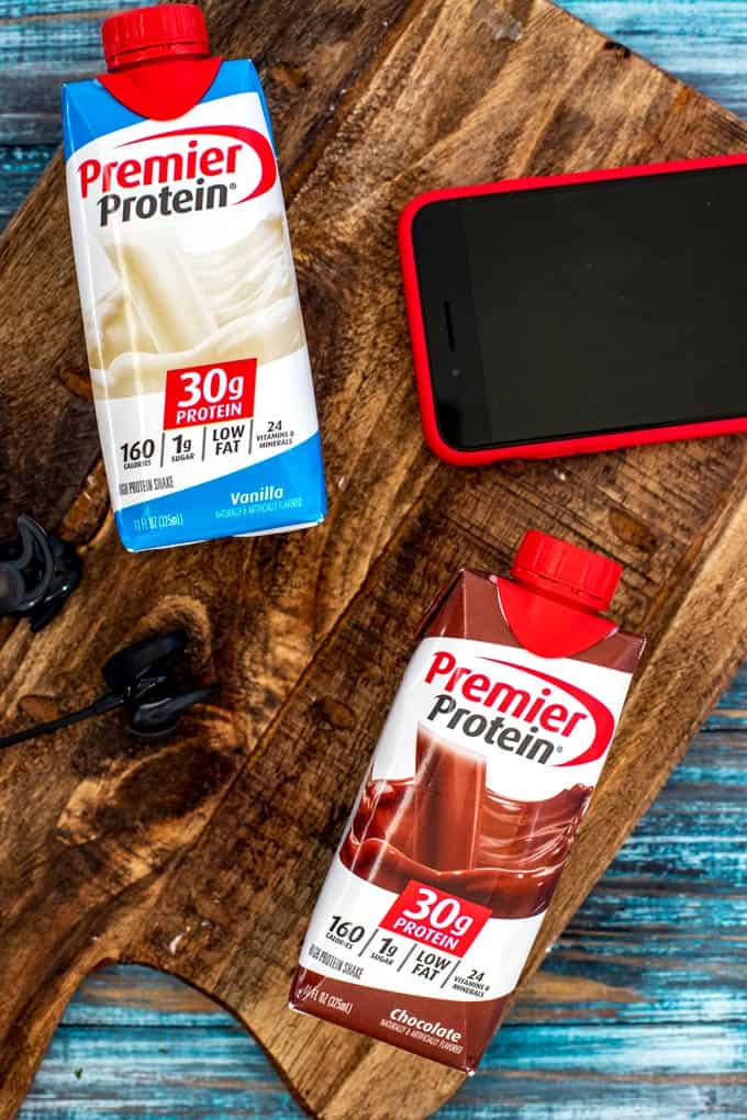 Chocolate and vanilla premier protein smoothies on a dark cutting board.