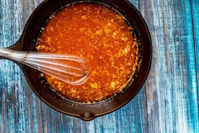 Sweet and Spicy Popcorn Butter being whisked together in a small cast iron skillet.