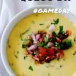 Photo of a homemade queso dip in a white bowl garnished with jalapenos and tomatoes with the text Homemade Queso Dip above.