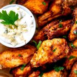 Close up photo of air fryer chicken wings with a small dish of blue cheese dressing.