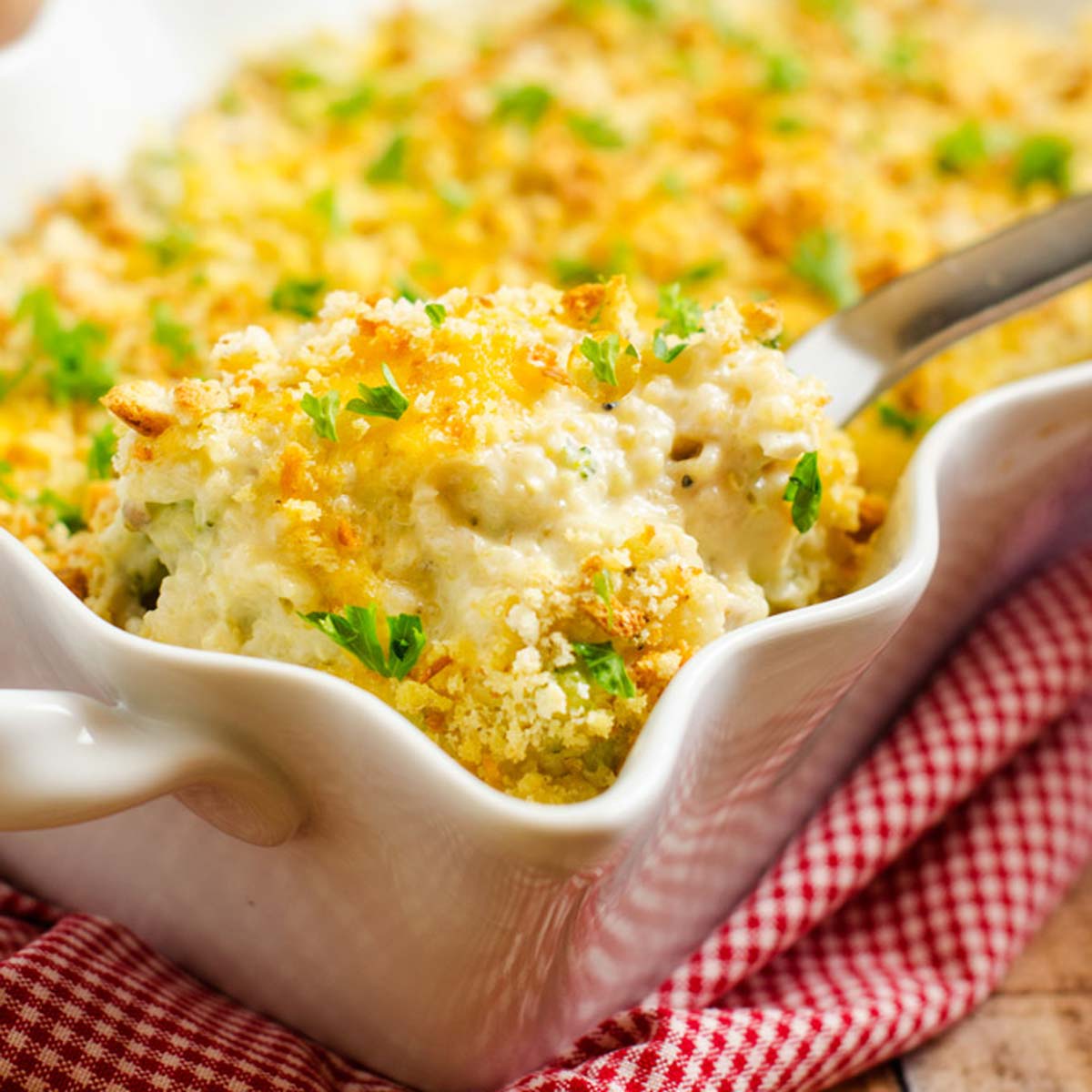 Square photo of a casserole dish with broccoli quinoa casserole with a spoonful being lifted out of it.