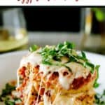 Photo of Eggplant Parmesan on a white plate garnished with basil sitting on a wooden background with the text Slow Cooker Eggplant Parmesan above it.