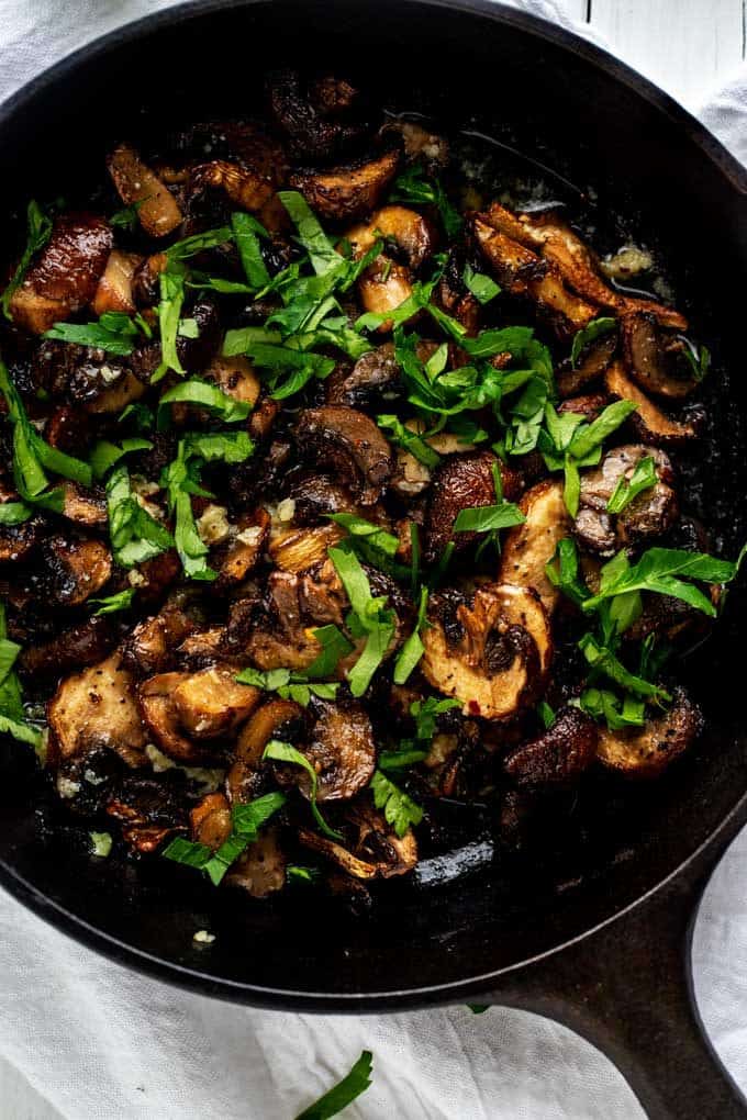 Overhead photo of Air Fryer Mushrooms in a small cast iron skillet garnished with parsley.