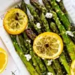 Close up overhead photo of Air Fried Asparagus on a white platter garnished with lemons.