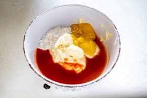 Photo of hot sauce, mayonnaise, mustard and sweetener in a small white bowl.