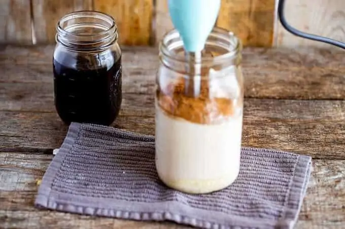 Photo of a mason jar with milk, cocoa powder, and Serve being mixed together with an immersion blender.