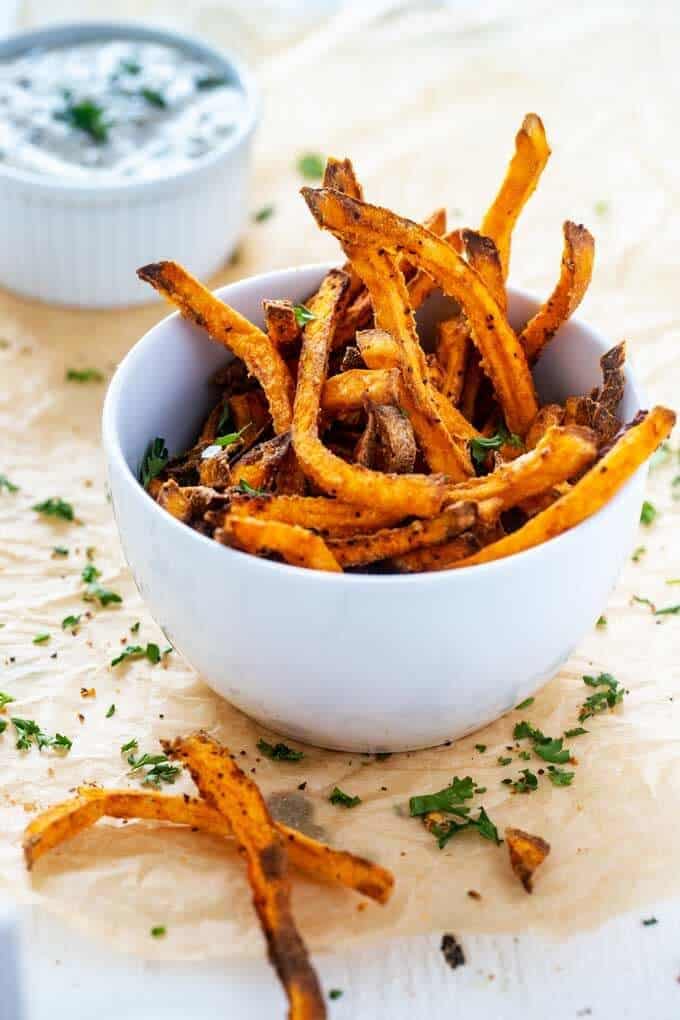Air Fryer Sweet Potato Fries in a white bowl garnished with parsley.