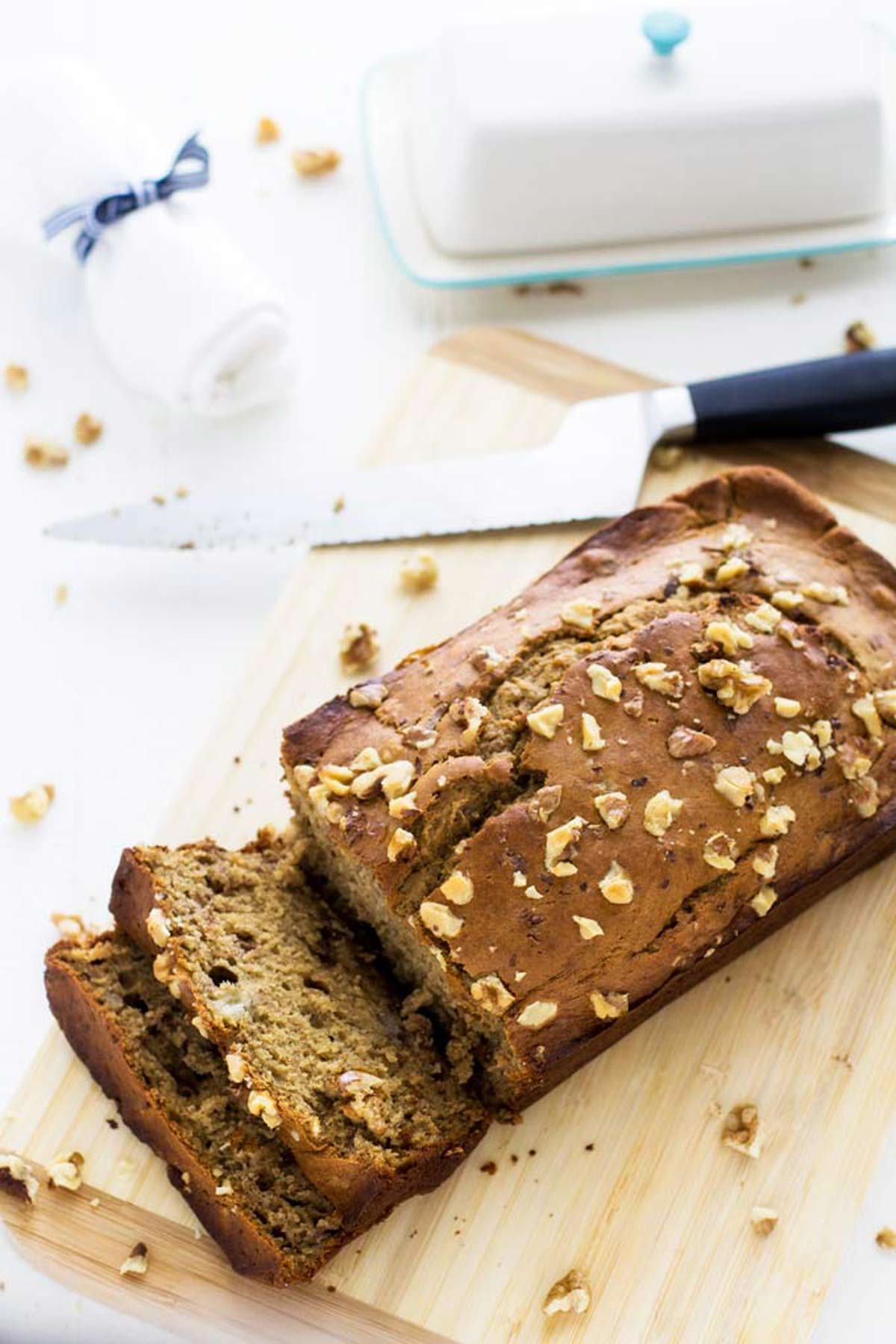 Overhead photo of quinoa banana bread on a wooden cutting board with a bread knife beside it.