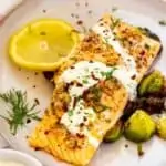 Square image of garlic salmon drizzled in a lemon dill sauce and garnished with dill.