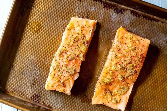 Photo of two garlic seasoned pieces of salmon ready to go in the oven.