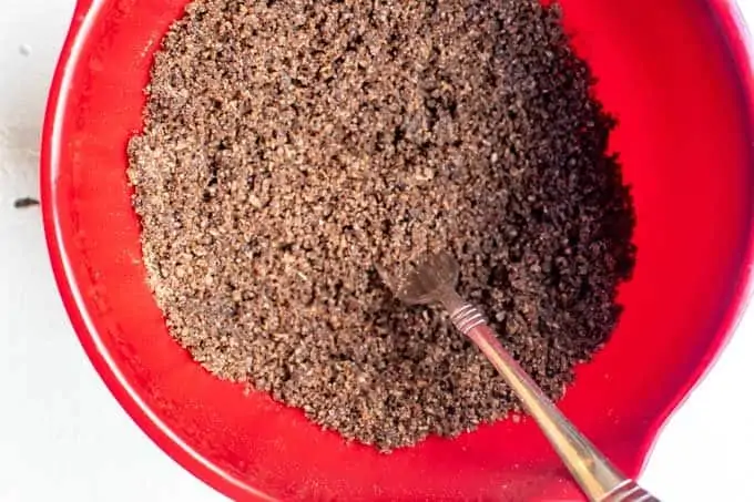 Photo of a red bowl with a chocolate cereal crust being mixed in it.