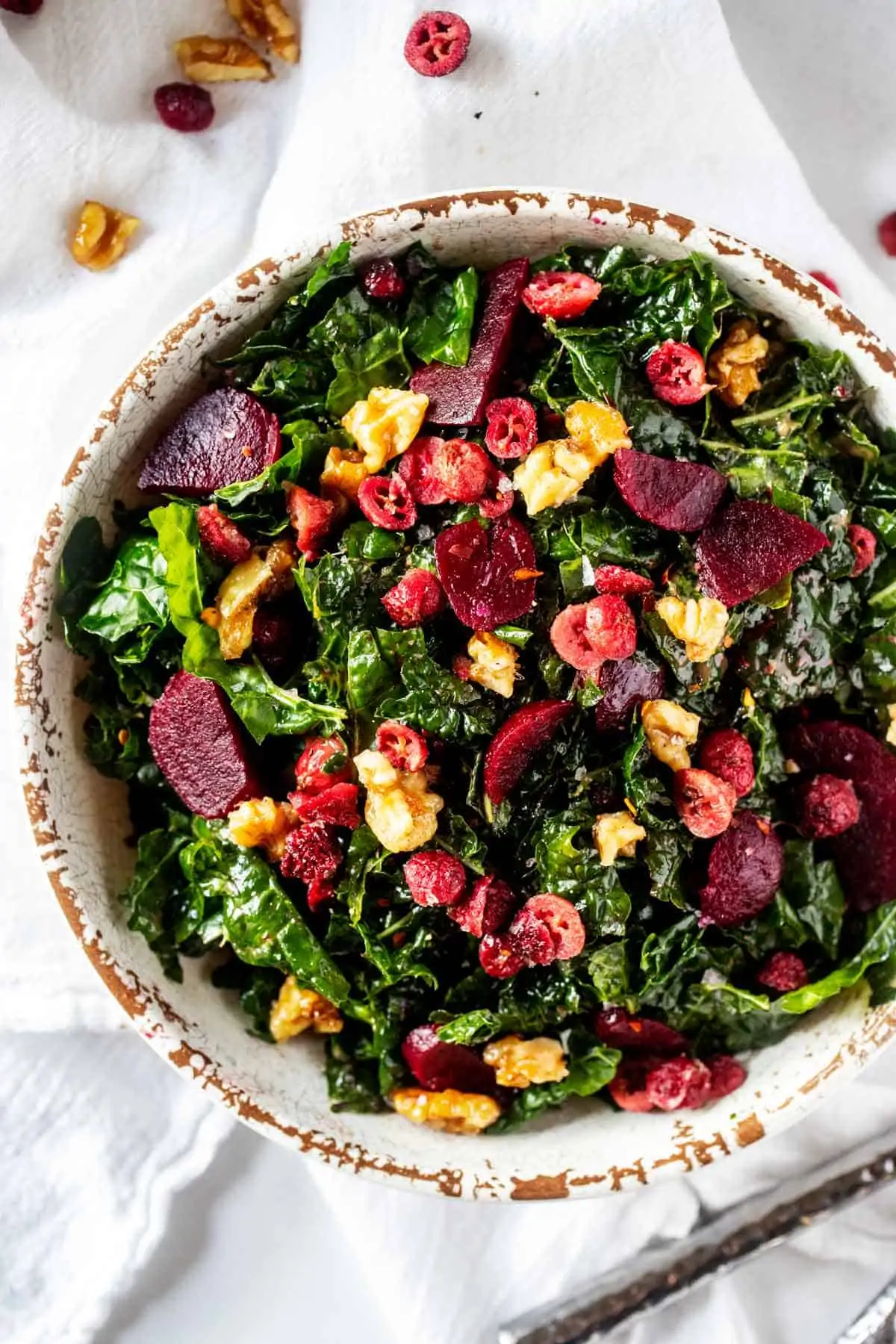 Close up overhead photo of a Kale Beet Salad in a rustic white bowl.