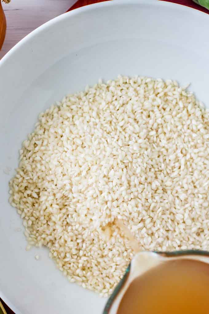 Photo of broth being poured over rice in a white bowl.