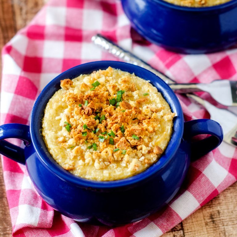 Square photo of quinoa mac and cheese in a blue crock on a checkered cloth napkin.