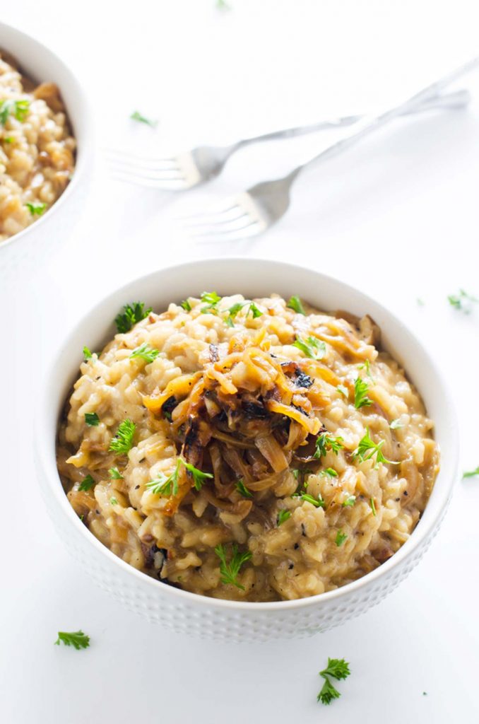 Photo of a white bowl of caramelized onion risotto with two forks behind it.