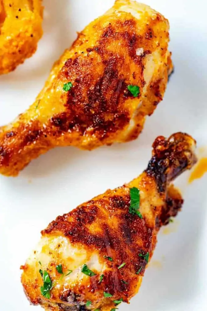 Photo of two air fried chicken legs on a white background.