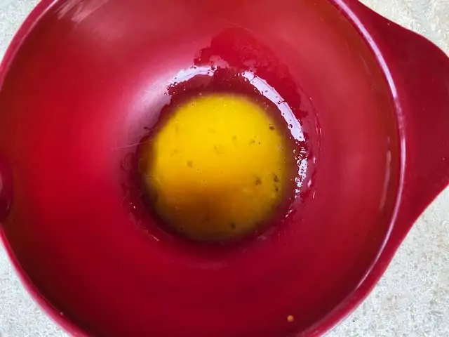 Beaten egg yolks in a red bowl.
